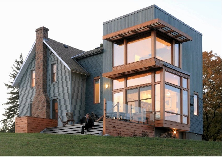 A modern ház tornácból, fából és üvegből épült.