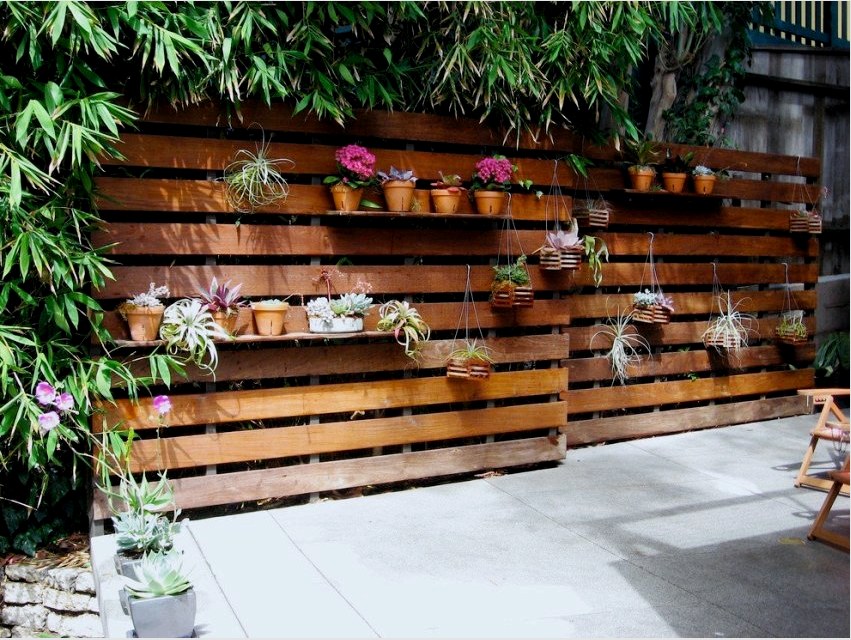 A ház kerítése raklapokból épül, és virágcseréphez szolgáló polcokkal egészíti ki