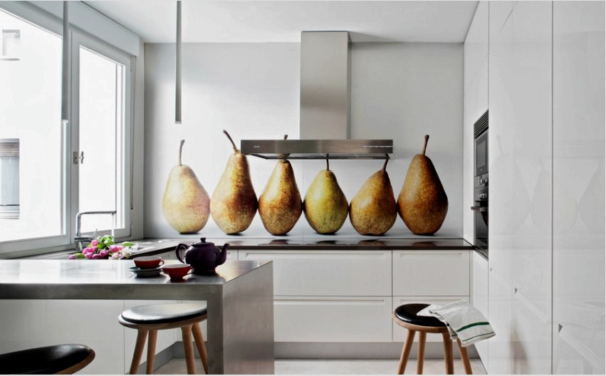 A nagy gyümölcsök egy üveg kötényen látványosnak tűnnek egy lakonikus fehér konyhában 