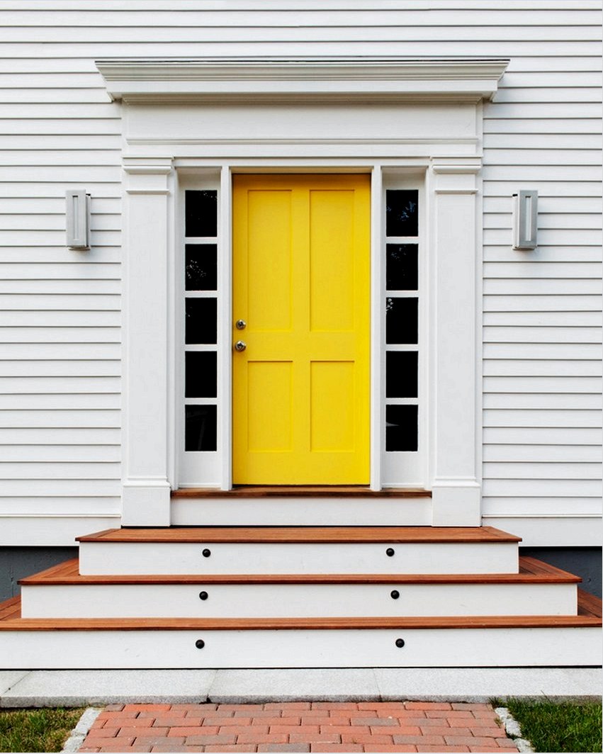 Világos sárga bejárati ajtó a ház fehér homlokzatán