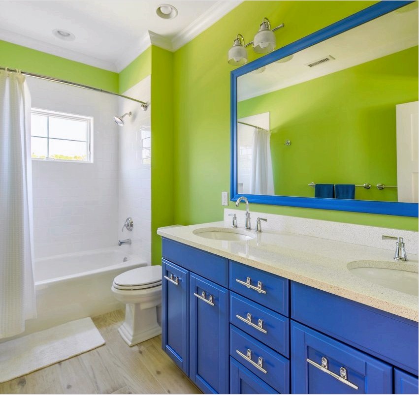 A fürdőszoba világos zöld falai jól illenek a fehér csempehez és a kontrasztos bútorokhoz