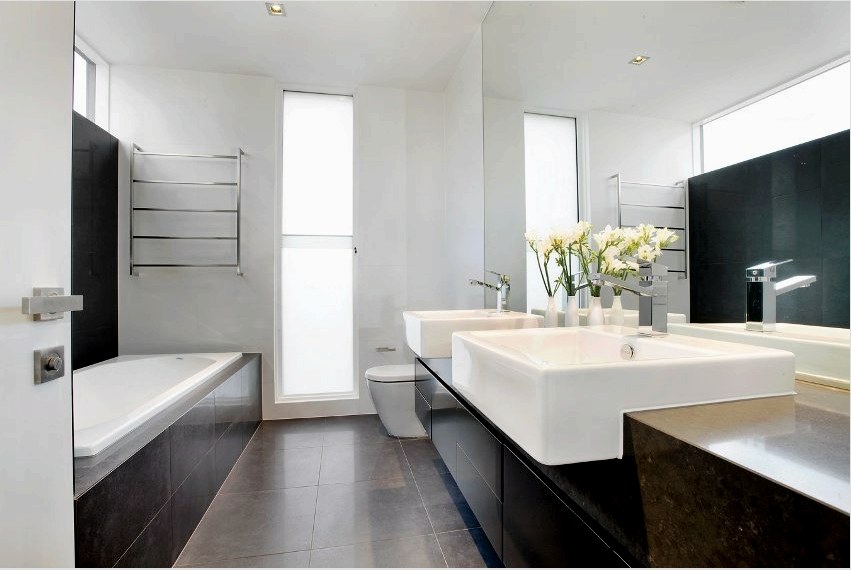 Fehér fürdőszoba falak sötét csempékkel és bútorokkal kombinálva
