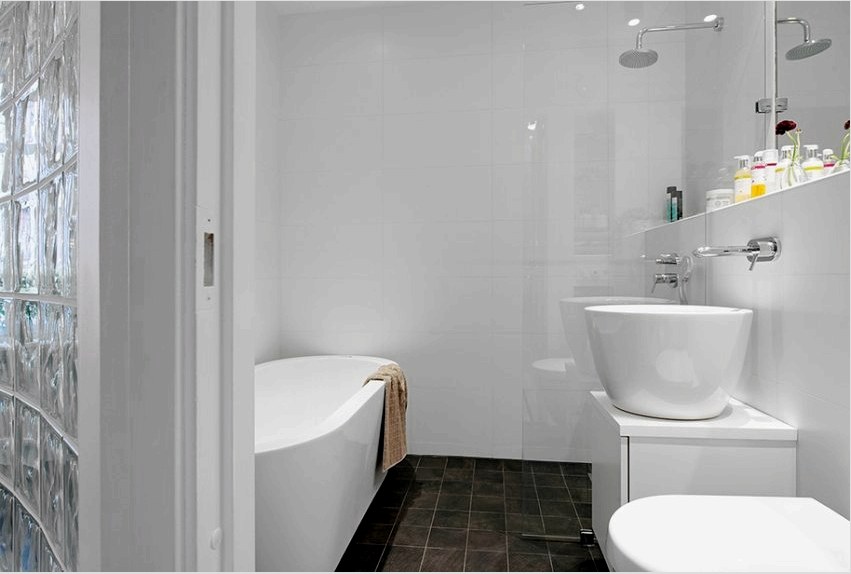 A fürdőszoba falain lévő fehér fényes csempe tisztaságot és tágasságot teremt.